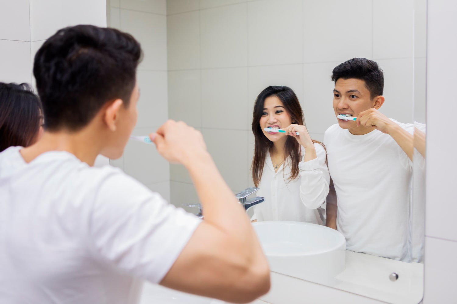 身穿白衣的年轻夫妇一起刷牙，照镜子