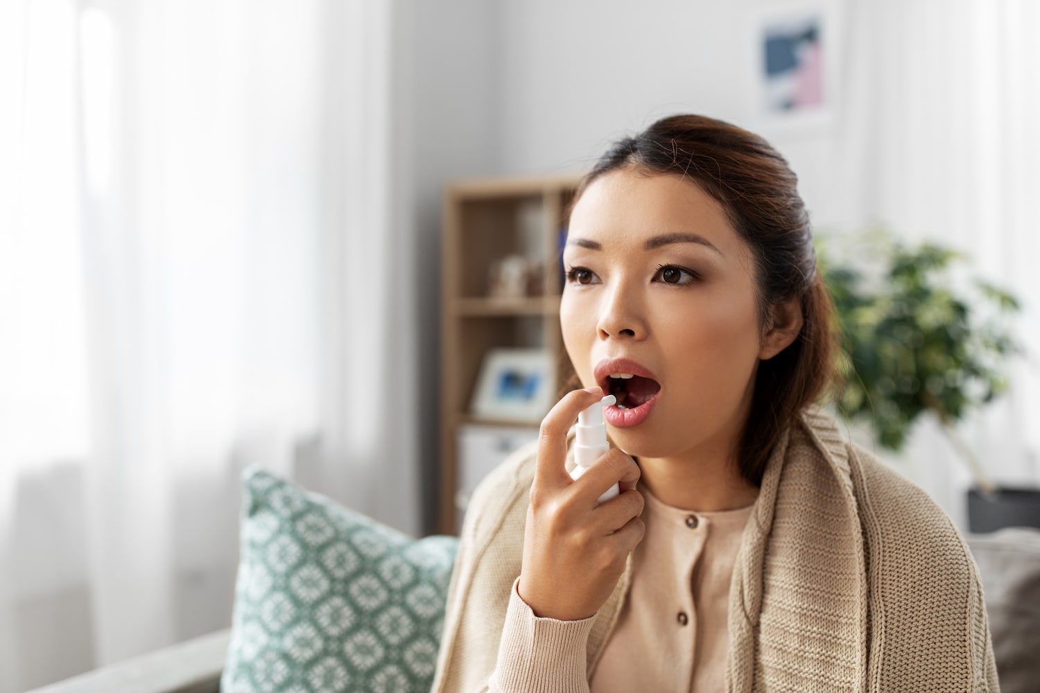 使用口腔喷雾剂的年轻女子